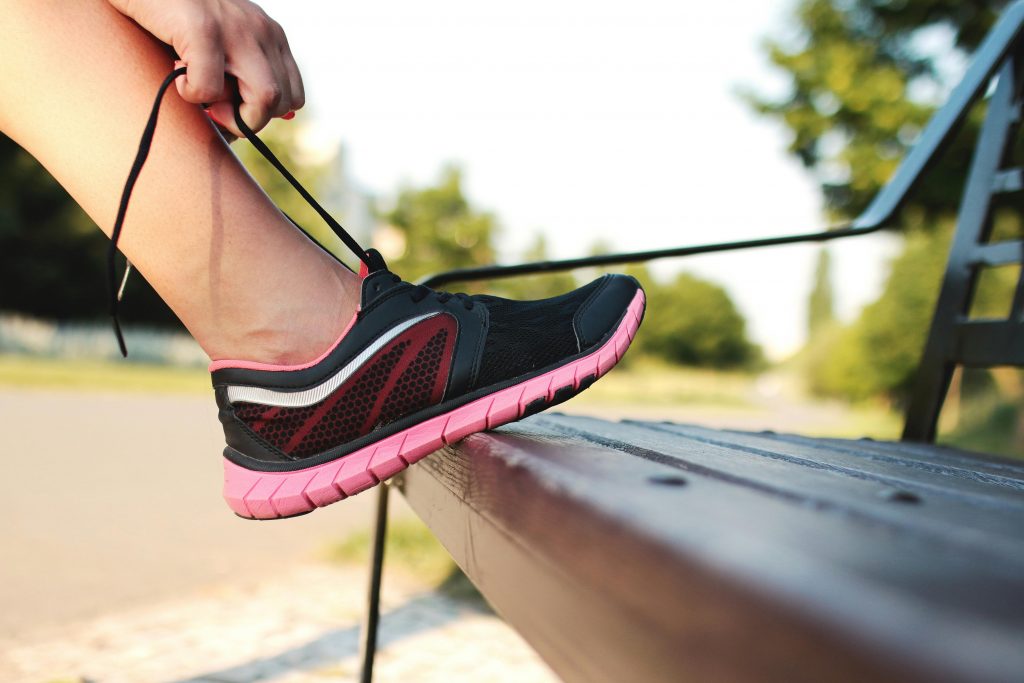 Person lacing up trainers on a bench